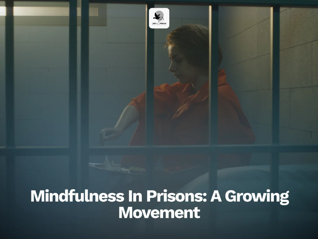 Person in an orange prison jumpsuit sits cross-legged behind bars, practicing mindfulness. Text reads, “Mindfulness In Prisons: A Growing Movement.